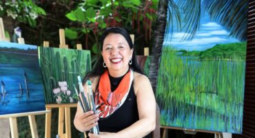 Elza Suzuki with canvas from the Cantos exhibition & Charms - Piratininga Lagoon. Photo: Disclosure / Macarena Lobos.